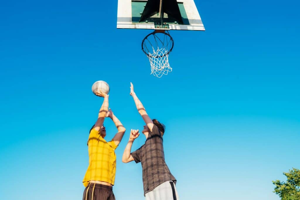 Two Young Caucasian Men Playing Basketball at the Park outdoor playground. Teenagers' hobby